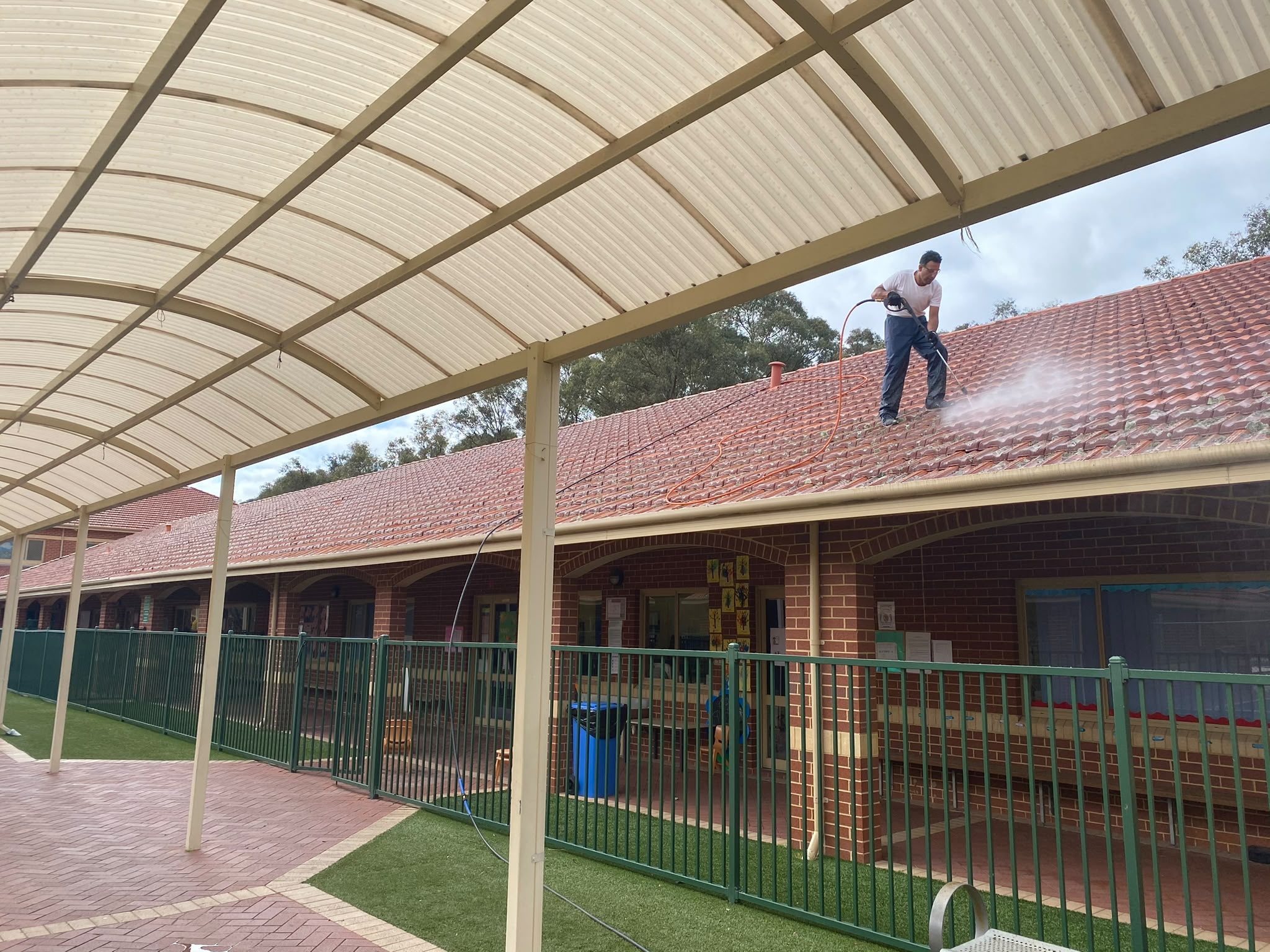 Seek Property Services Pty Ltd tradesman pressure washing and preparing commercial tile roof